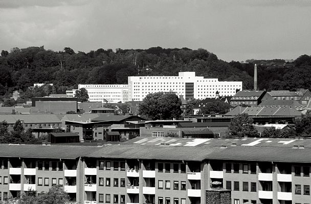 Vejle Amts og Bys Sygehus ligger smukt og klart med den hvide bygningskrop på baggrund af de mørkegrønne, skovklædte skråninger, der favner Vejle. - Historie - C.F. Møller